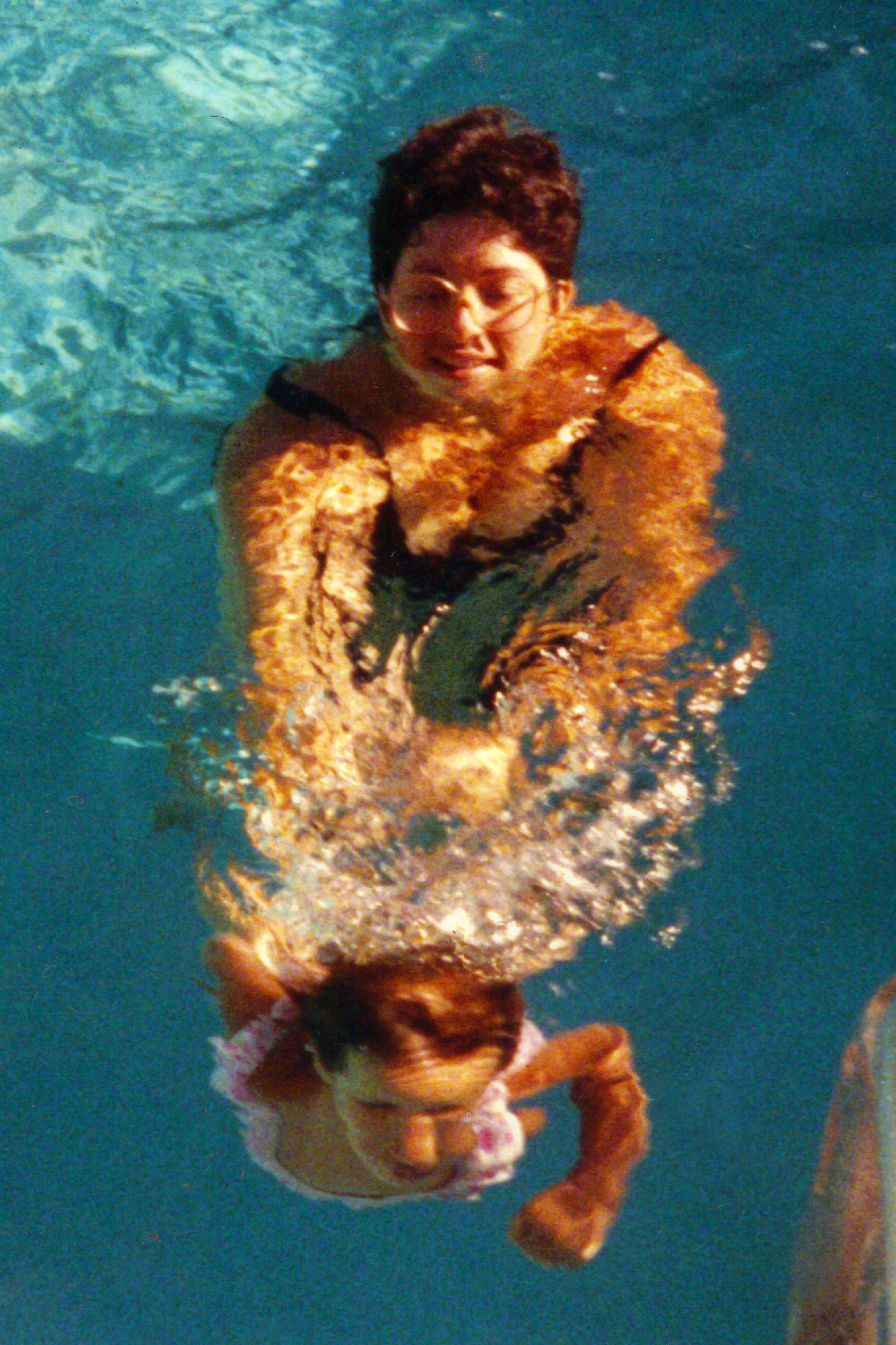 Kim swimming underwater at 2 years old